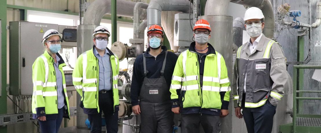 Foto: Doris Mißelich (l.) erklärte Dr. Arndt Selbach, Leiter des Evonik-Standorts Wesseling (r.), gemeinsam mit ihren Kollegen die Anpassungen im Produktionsprozess. Dieser zeigte sich begeistert von der Idee und freute sich, stellvertretend für das Unternehmen, die Prämie zu überreichen. Quelle: Evonik